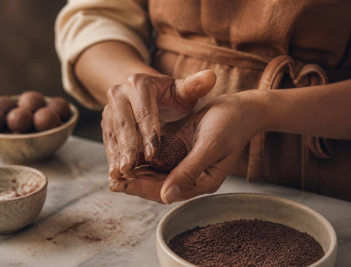 Manos enrollando un brigadeiro sobre mármol
